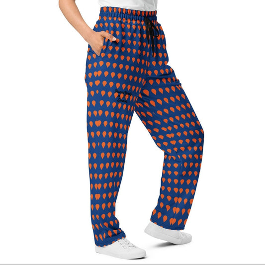 A model wearing the Thames Flow Joggers, showing the wide-leg, relaxed silhouette and the orange drop print on the deep navy blue background.
