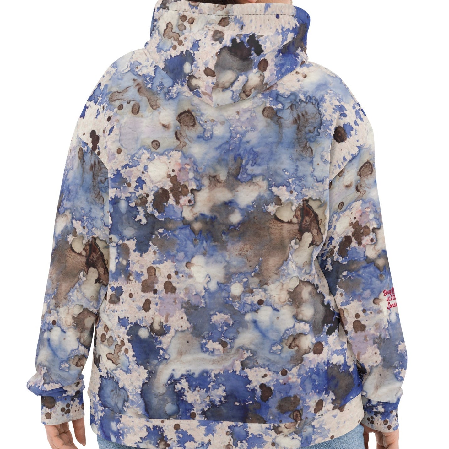 A model wearing the Amalfi Resort Hoodie. The image showcases the fluid light blue, beige, and brown "beach splash" print against a minimalist background, highlighting the relaxed, high-fashion silhouette.