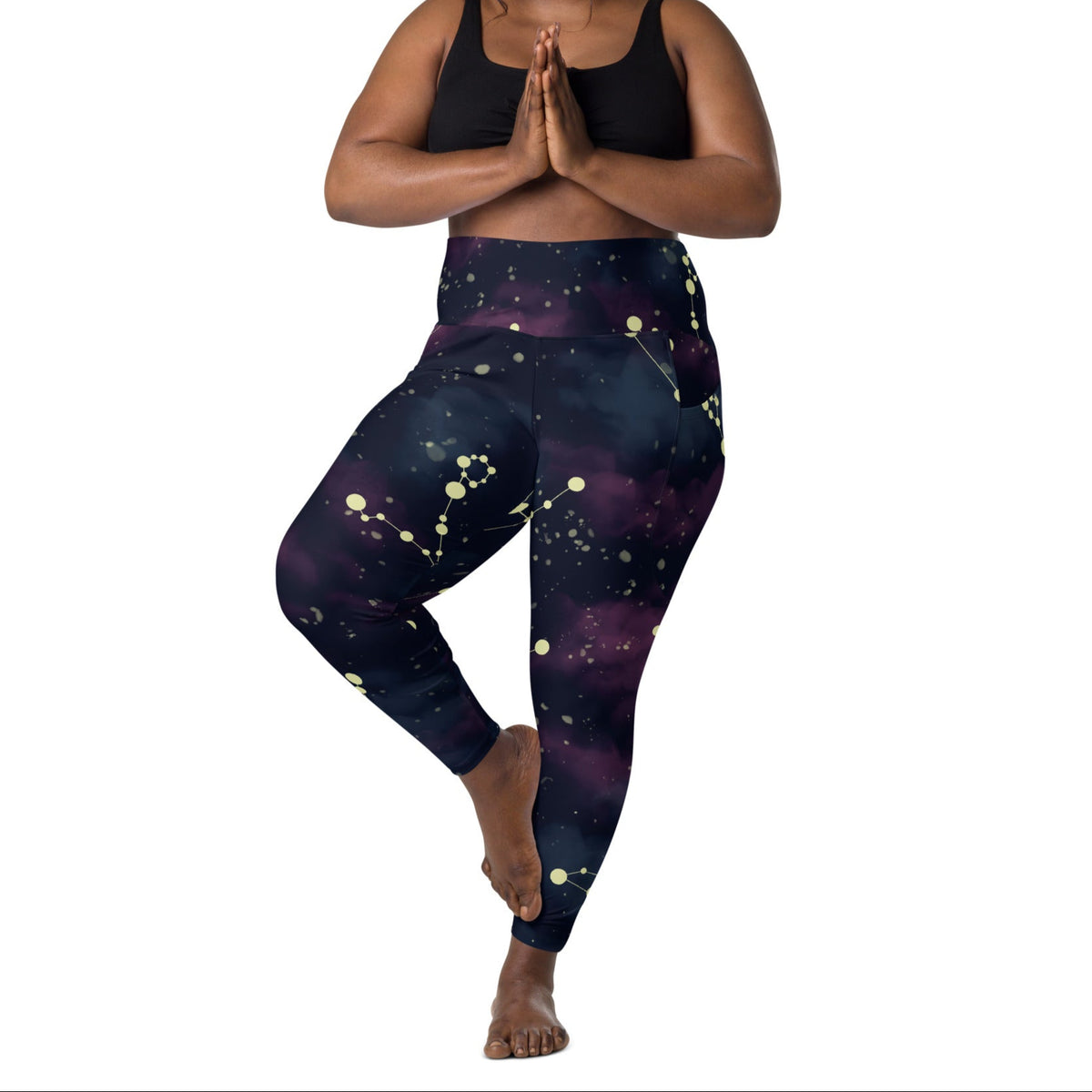 A model wearing The Andromeda Sculpt Leggings, showcasing the sculpting fit and the distinctive yellow star constellation print on the dark purple-to-black gradient fabric. The background features a subtle cosmic nebula.