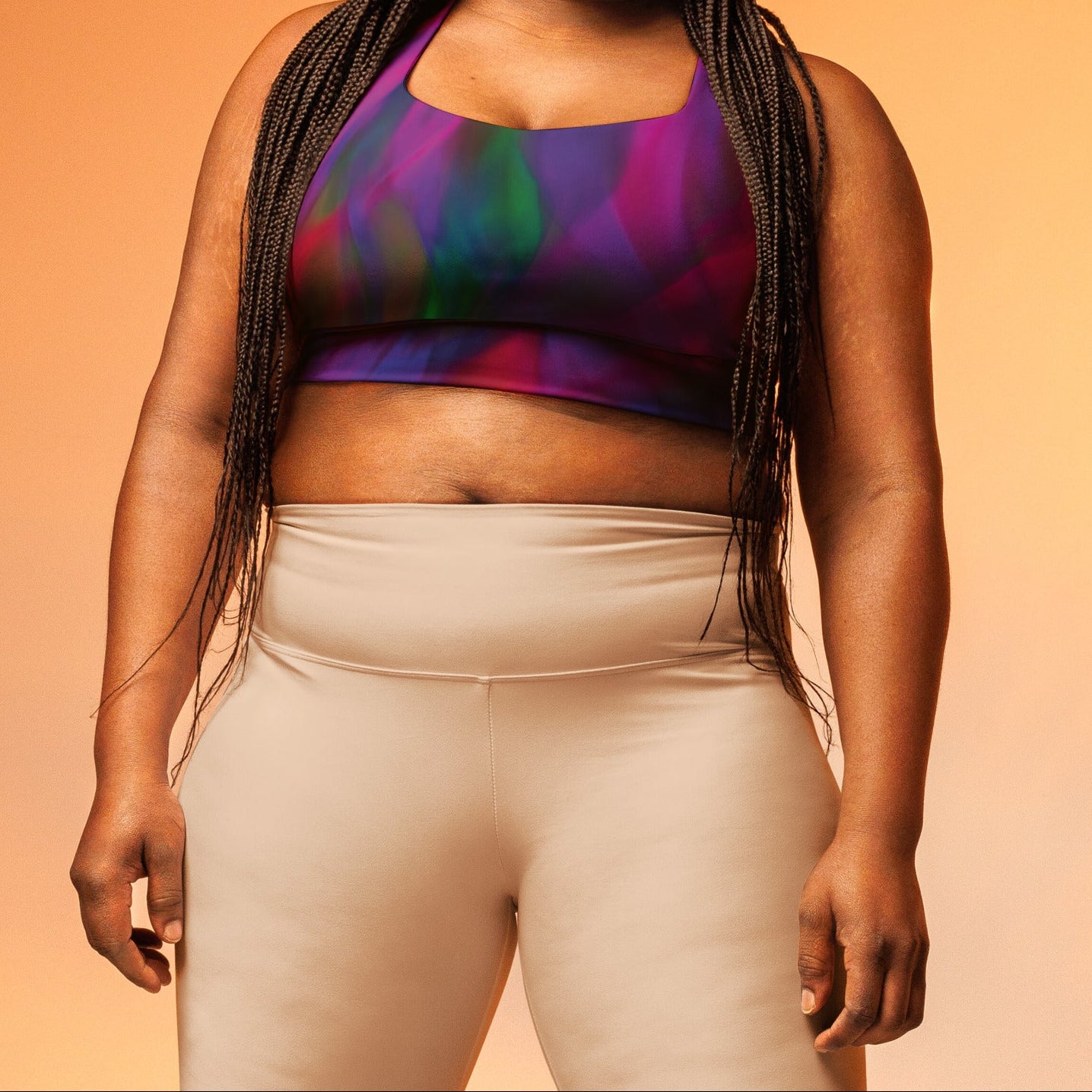 A model wearing The Bologna Longline Performance Bra, showing the longline cut and the vibrant graphic blend of purple, pink, and green hues.