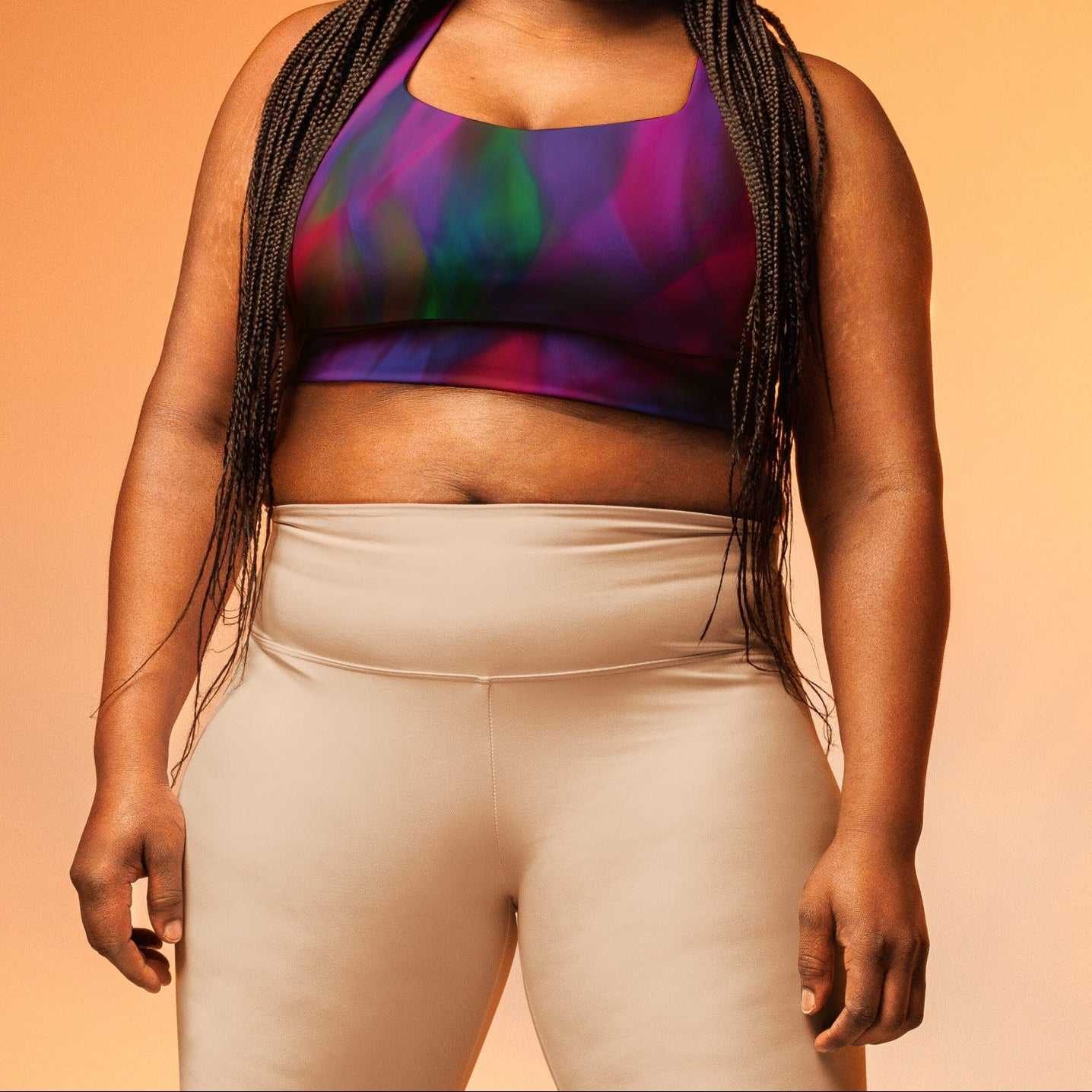 A model wearing The Bologna Longline Performance Bra, showing the longline cut and the vibrant graphic blend of purple, pink, and green hues.