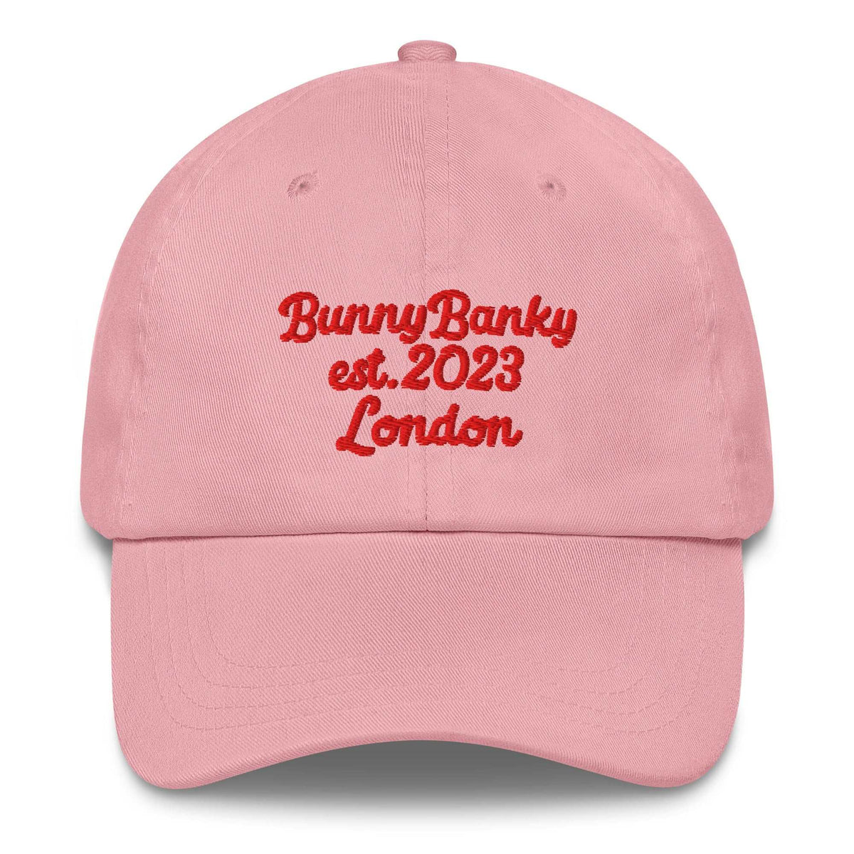 A close up of The Heritage Cap in pink showing the heritage branded signature embroidered in red