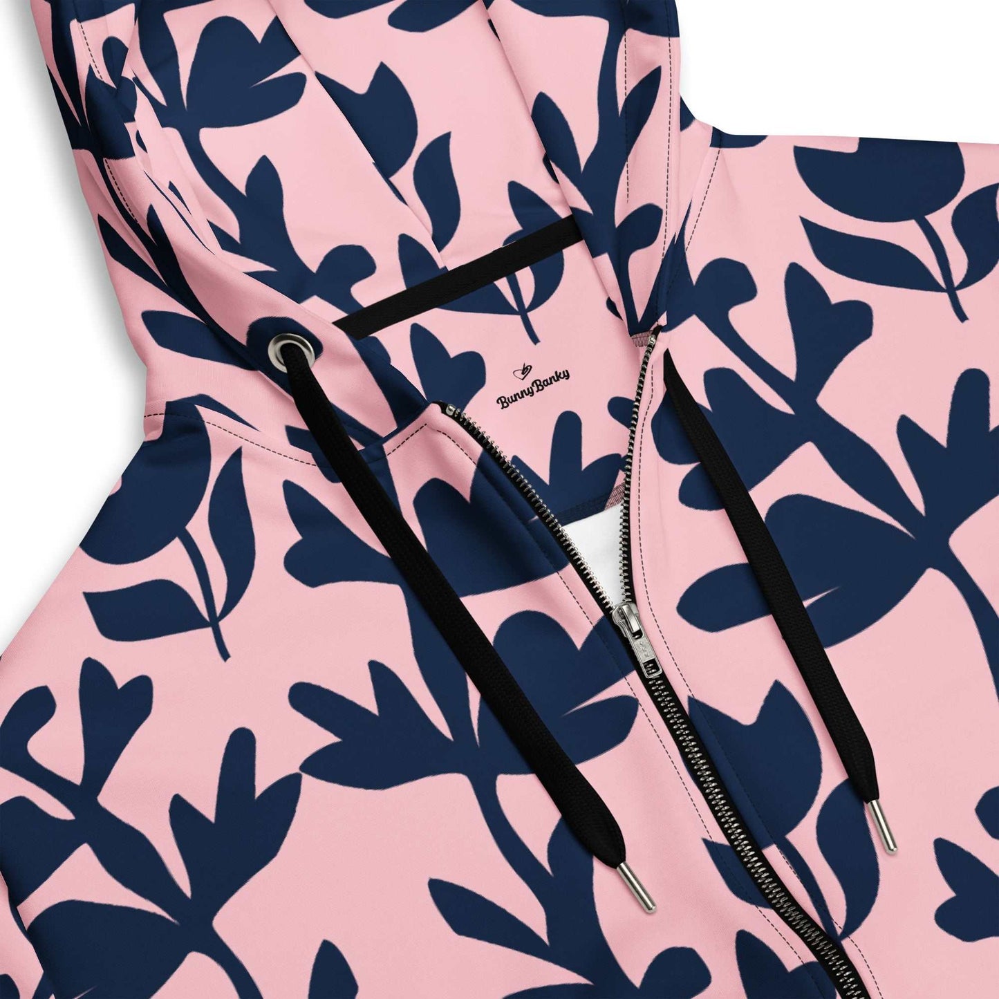 A model wearing The Kensington Zip Hoodie, showing the full-zip closure and the oversized pink and blue floral print across the recycled polyester fabric.