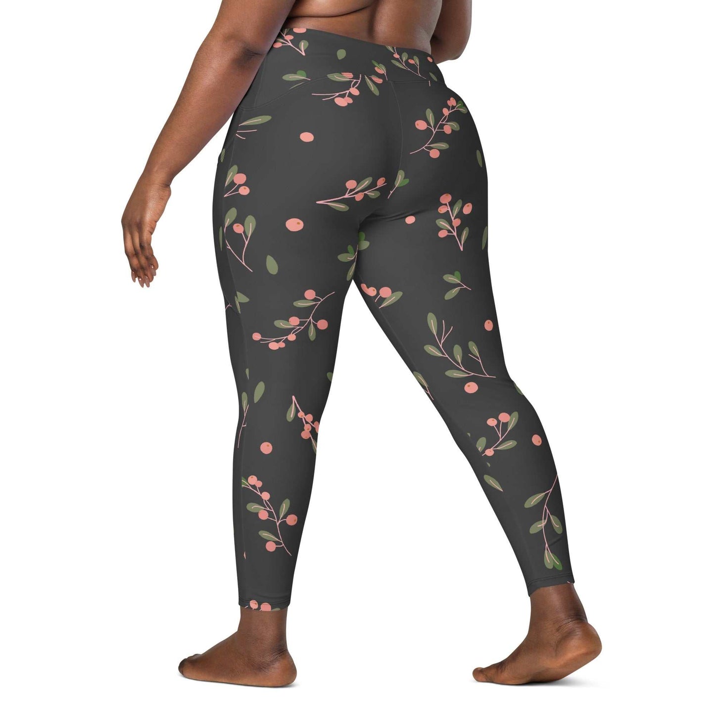 Plus size woman wearing high-waisted Manchester Sculpt Leggings with pink floral print on khaki green background, showing mild compression and dual side pockets.