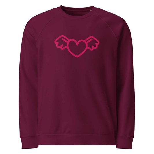 A close-up of The Monument Organic Sweatshirt, showing the detailed embroidery of a vibrant pink heart with wings on the 100% organic cotton fabric.