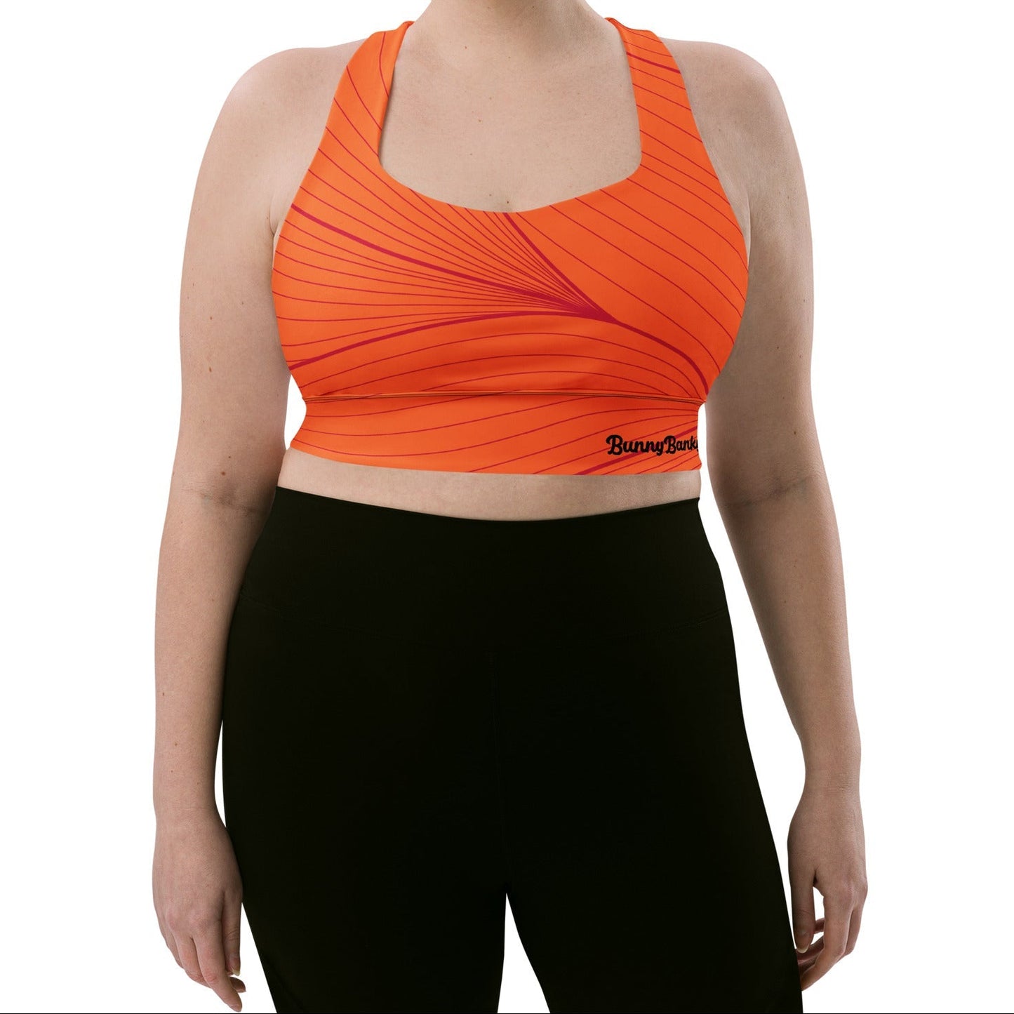 Model wearing the Rhodes Longline Performance Bra in vibrant orange geometric lines on orange background with the iconic logo and signature print at the back