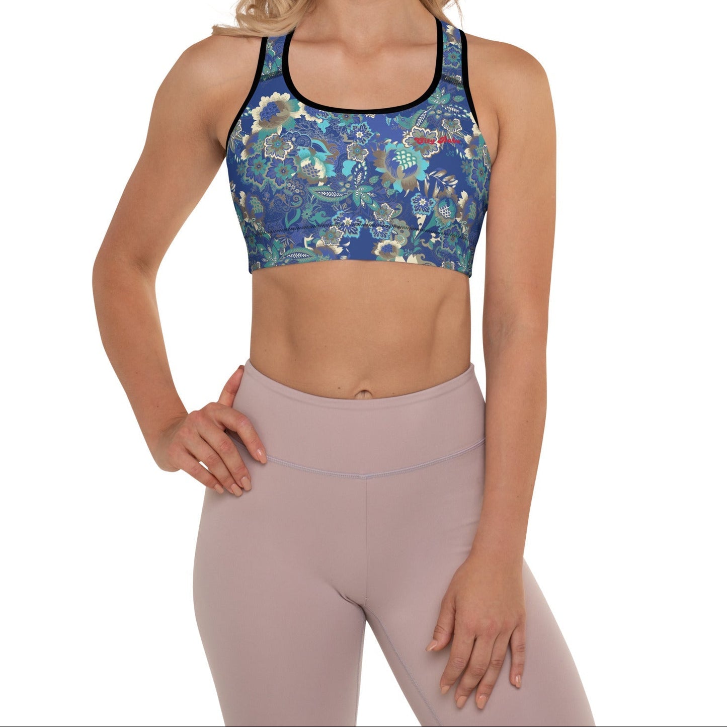 A model wearing The Rio Performance Bra, showing the supportive fit and the vibrant bright blue floral print with City Babe on the top left. Highlights the garment's construction from technical polyester.