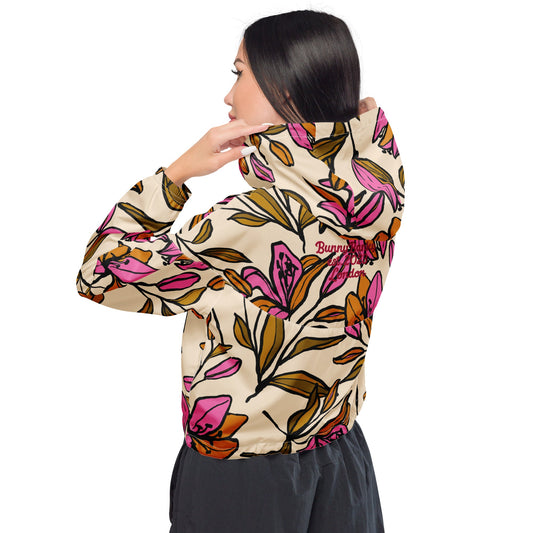 A model wearing The Terra Shell, showing the lightweight fit and the vibrant bubblegum pink tropical floral print on the beige fabric.