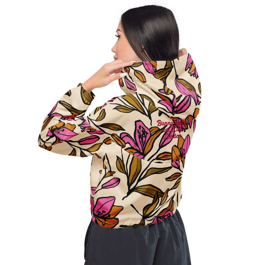 A model wearing The Terra Shell, showing the lightweight fit and the vibrant bubblegum pink tropical floral print on the beige fabric.