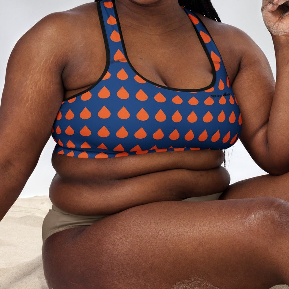 A model wearing The Thames Performance Bra, showing the supportive fit and the sophisticated orange drops print on the deep navy blue background. Highlights the garment's construction and the City Babe text printed in black on the top left