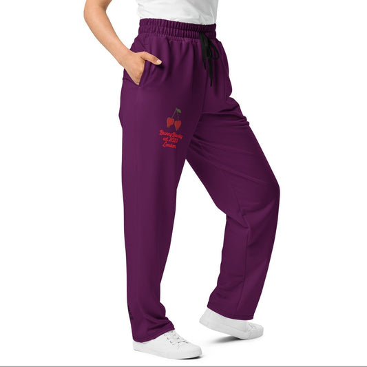 A model wearing The Tokyo Purple Flow Wide Joggers, showing the relaxed, wide-leg cut and the playful Pop Cherry print on the dark purple fabric.