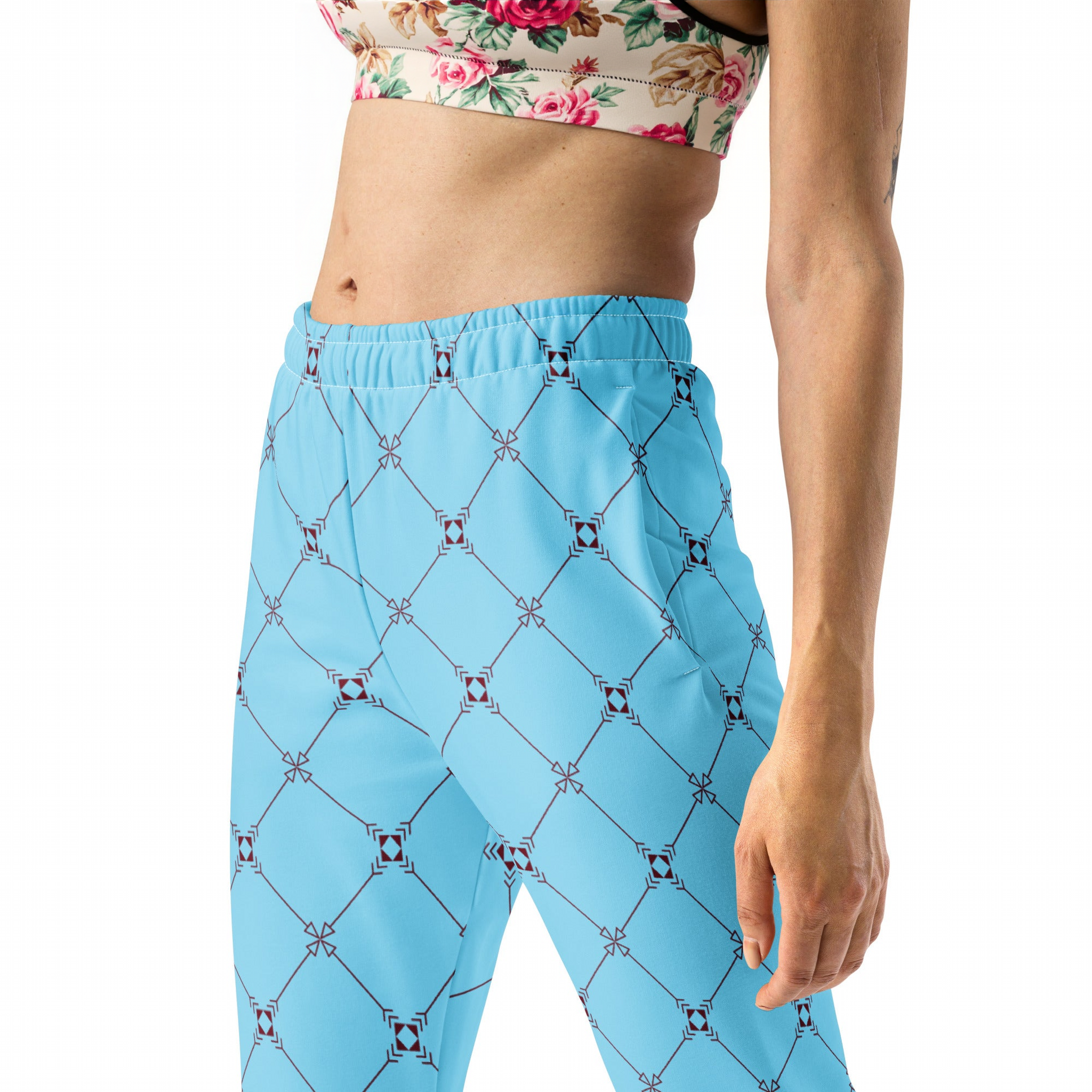 A model wearing the Belgravia Slim Fit Joggers in the burgundy monogram print, showing the tailored fit, and the Monaco Performance Bra against the light blue background.