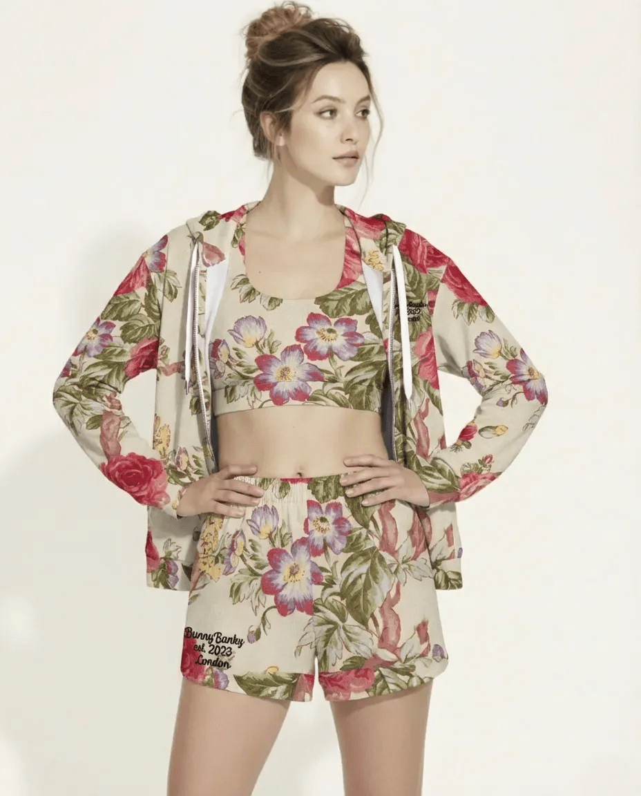 A BunnyBankY AI proprietary model wearing the Evergreen Zip Hoodie, showcasing the elaborate red rose and green vine vintage print on a sustainable cream fabric.