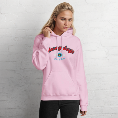 Person wearing a pink hoodie with away days and crownprint against a white brick wall.