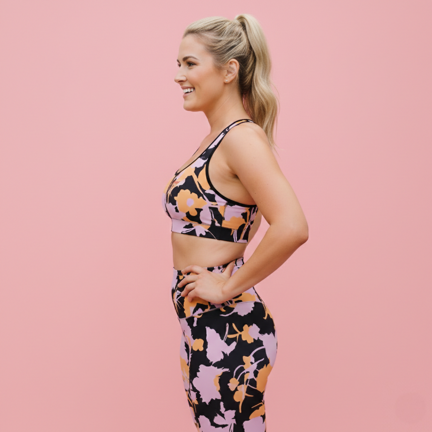 AI BunnyBankY model wearing The Miami Performance Bra, showing the supportive fit and the vibrant pink and orange splashes print.