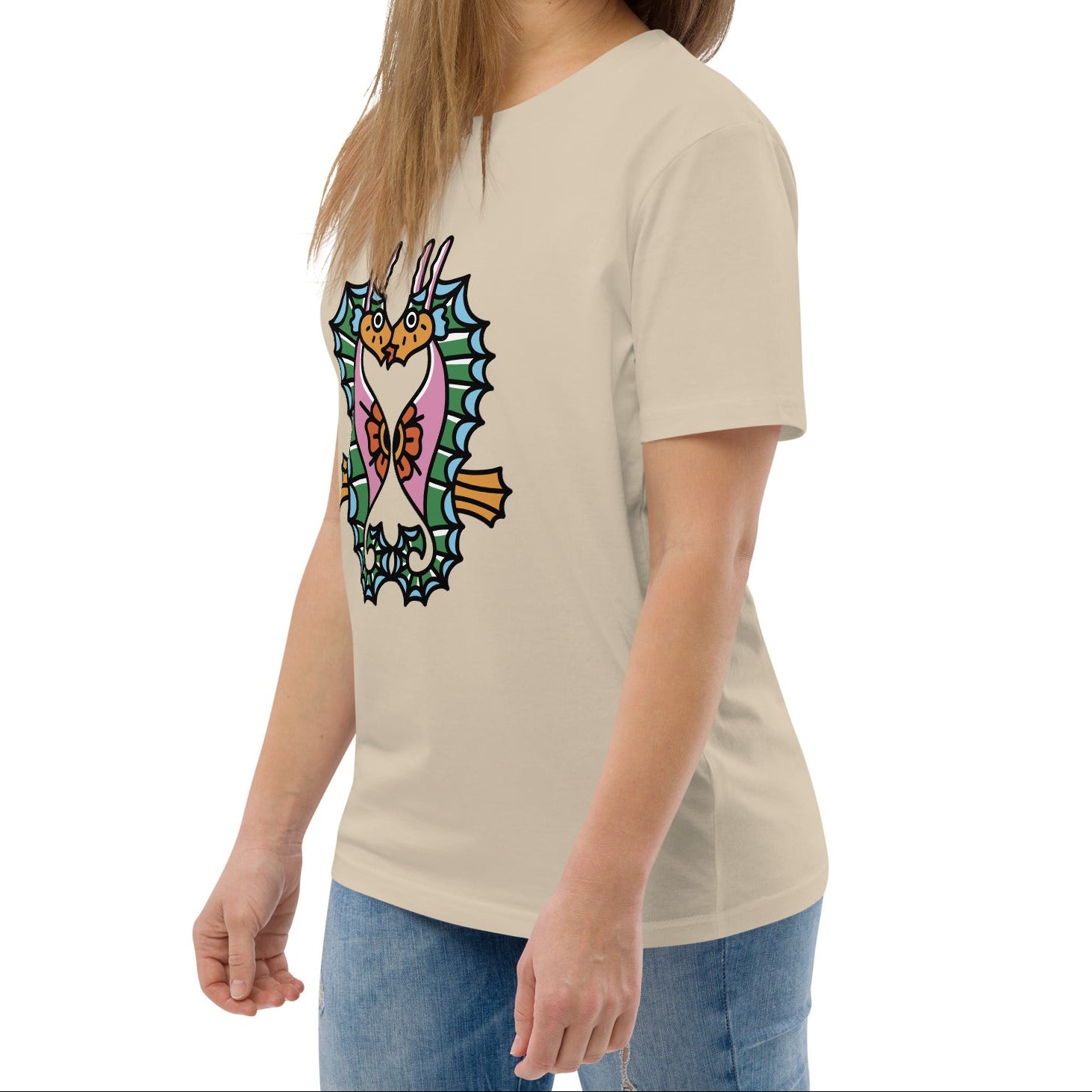 A dusty beige organic t-shirt featuring a symmetrical graphic of two colorful seahorses with bunny ears and floral details.