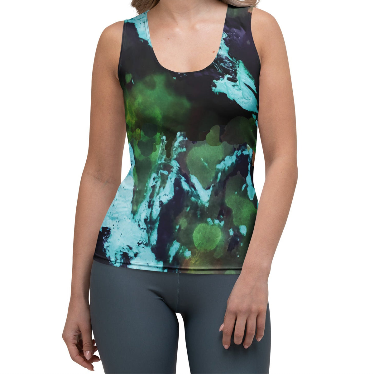 A woman modeling  the abstract flow performance tank, a a sleeveless athletic tank top with a green, teal, and black abstract watercolor pattern, paired with gray leggings, against a plain white background.