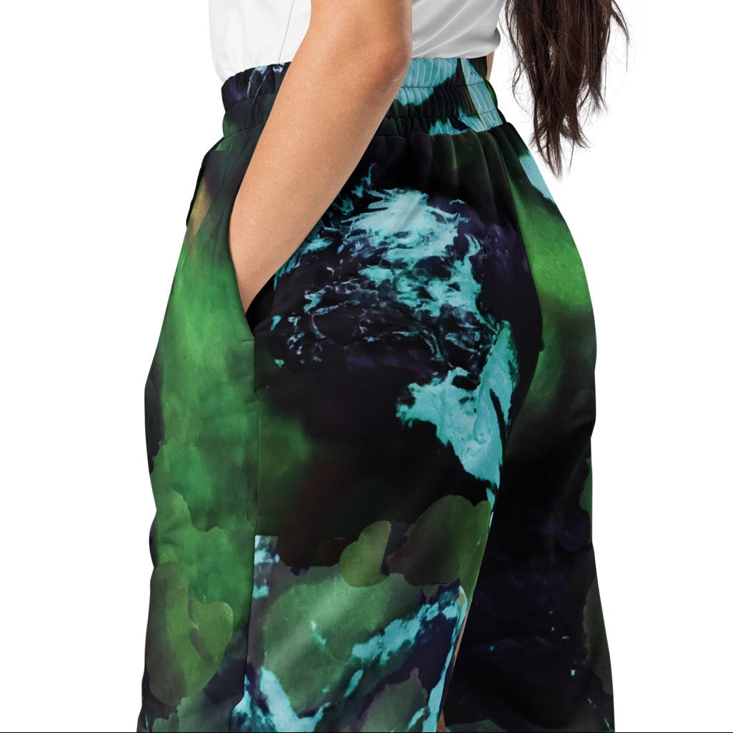 A model wearing The Abstract Flow Joggers, showing the wide-leg cut and the abstract expressionism-inspired print in green and blue hues.