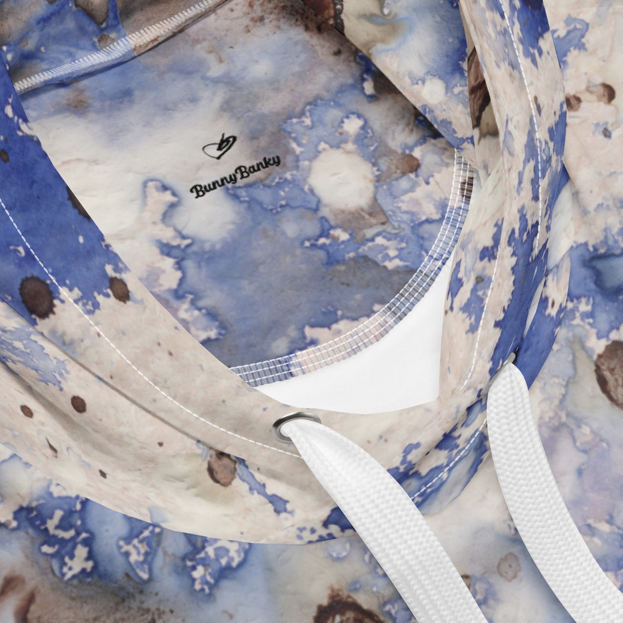 A close-up view of the Amalfi Resort Hoodie. The shot focuses on the intricate splash pattern and the soft, premium texture of the recycled fabric, showing the vibrant light blue and earthy tonal details.