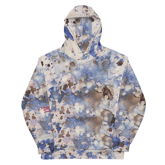 A close-up view of the Amalfi Resort Hoodie. The shot focuses on the intricate splash pattern and the soft, premium texture of the recycled fabric, showing the vibrant light blue and earthy tonal details.