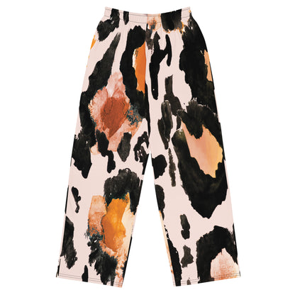 The Amazonia Flow Joggers. Wide-leg pants featuring an abstract watercolor animal print pattern in black, orange, and peach on a light pink background.