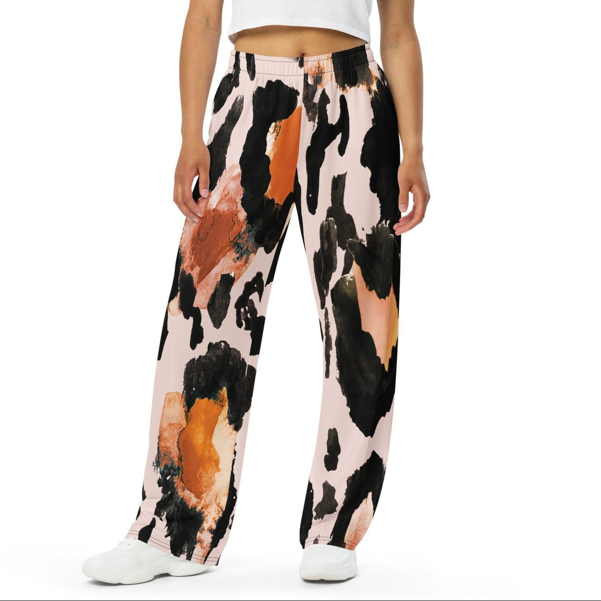 The Amazonia Flow Joggers, a pair of wide-leg pants featuring an abstract watercolor-style print with black, orange, and peach paint strokes on a light pink base, shown against a plain white background.