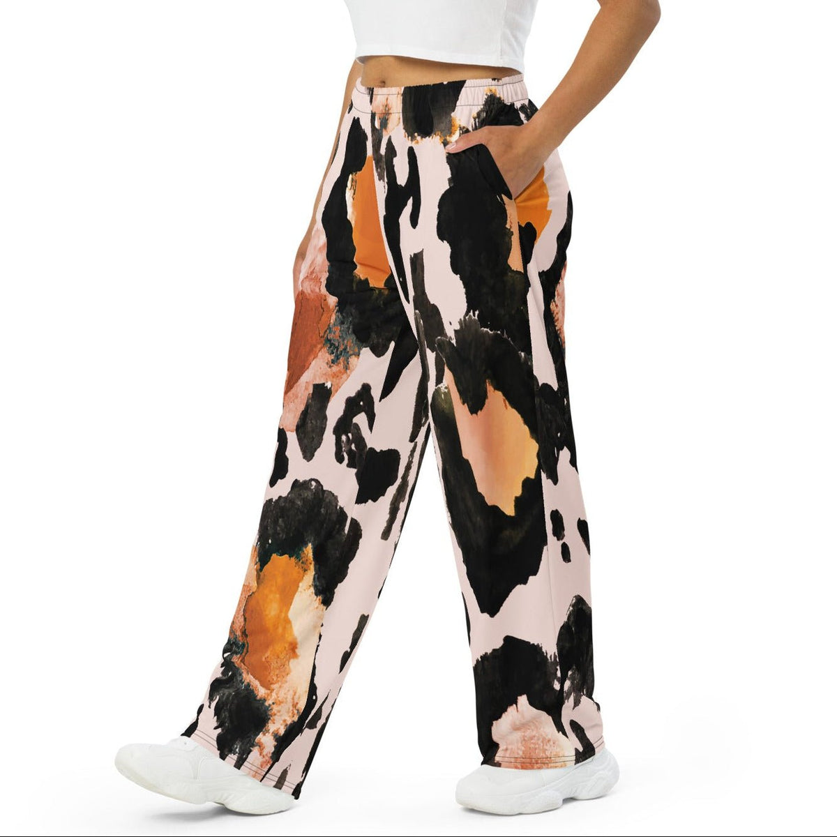 The Amazonia Flow Joggers, a pair of wide-leg pants featuring an abstract watercolor-style print with black, orange, and peach paint strokes on a light pink base, shown against a plain white background.