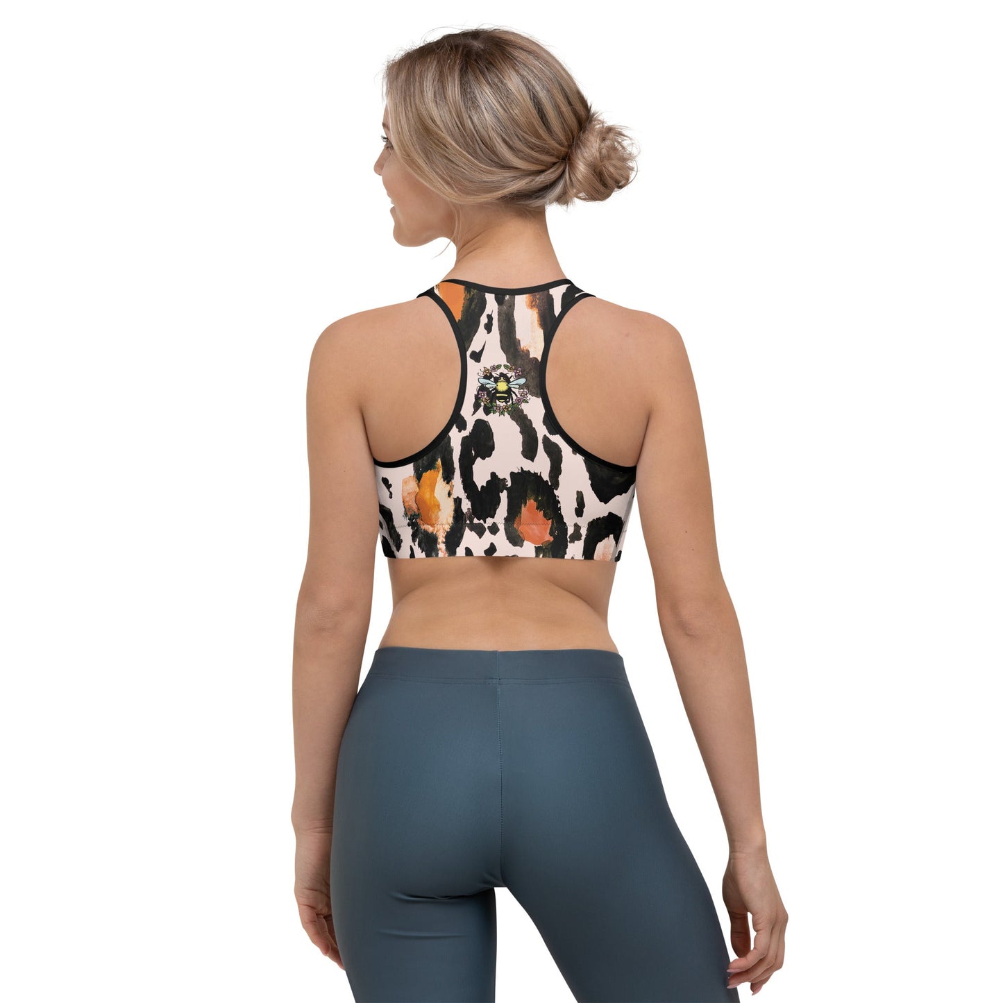 A model wearing The Amazonia Performance Bra, highlighting the small bee print and the secure racerback design on the animal print fabric.