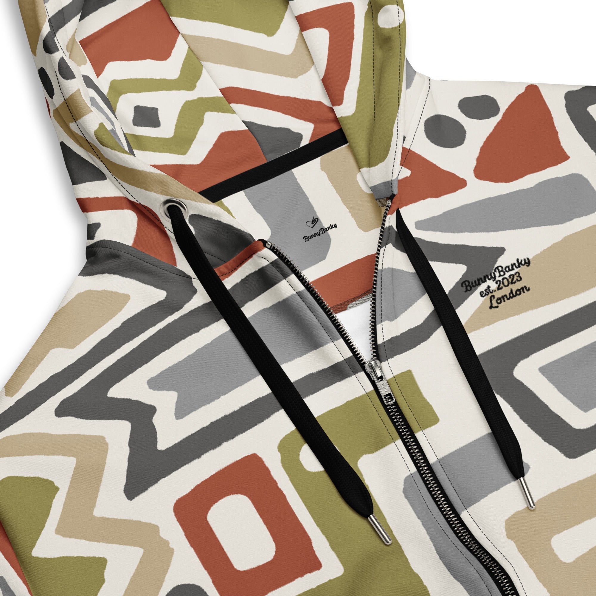 Close-up of The Amsterdam Zip Hoodie fabric, highlighting the textured, earthy tones of the geometric pattern and the soft feel of the 95% recycled polyester.