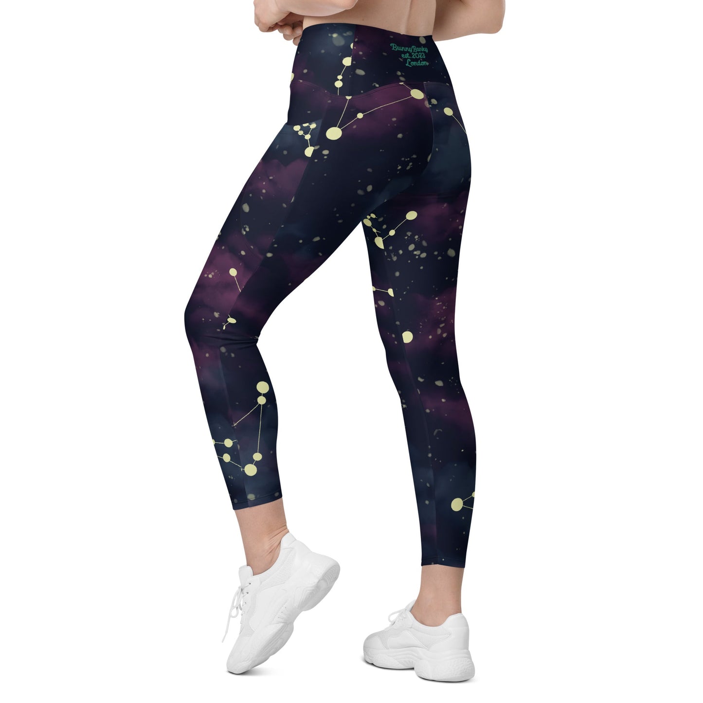 A BunnyBankY AI proprietary model wearing The Andromeda Sculpt Leggings, showcasing the sculpting fit and the distinctive yellow star constellation print on the dark purple-to-black gradient fabric. The background features a subtle cosmic nebula.