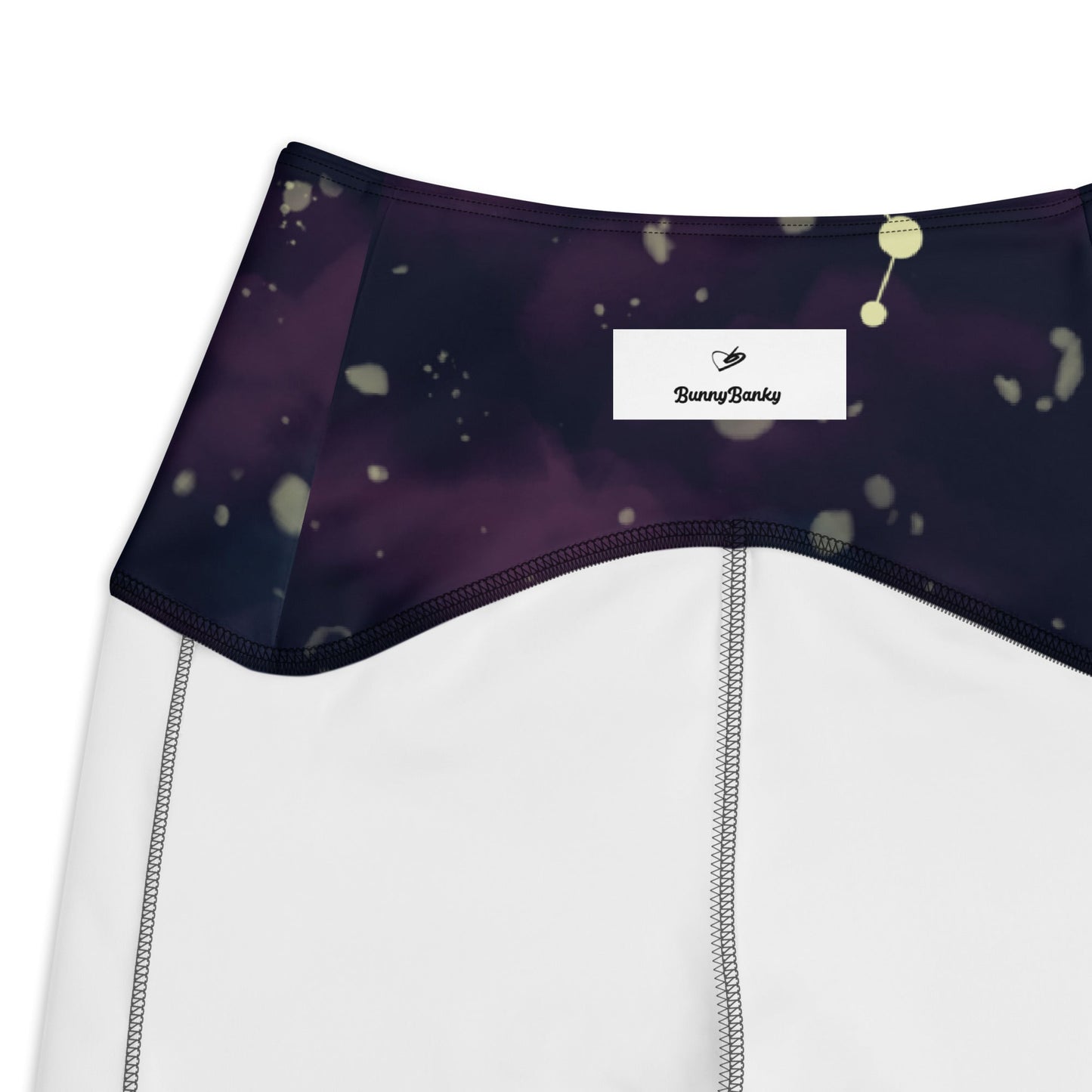 A close up of The Andromeda Sculpt Leggings, showcasing the sculpting fit and the distinctive yellow star constellation print on the dark purple-to-black gradient fabric. The background features a subtle cosmic nebula.