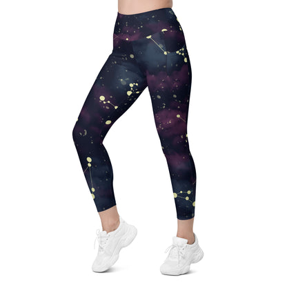 A model wearing The Andromeda Sculpt Leggings, showcasing the sculpting fit and the distinctive yellow star constellation print on the dark purple-to-black gradient fabric. The background features a subtle cosmic nebula.