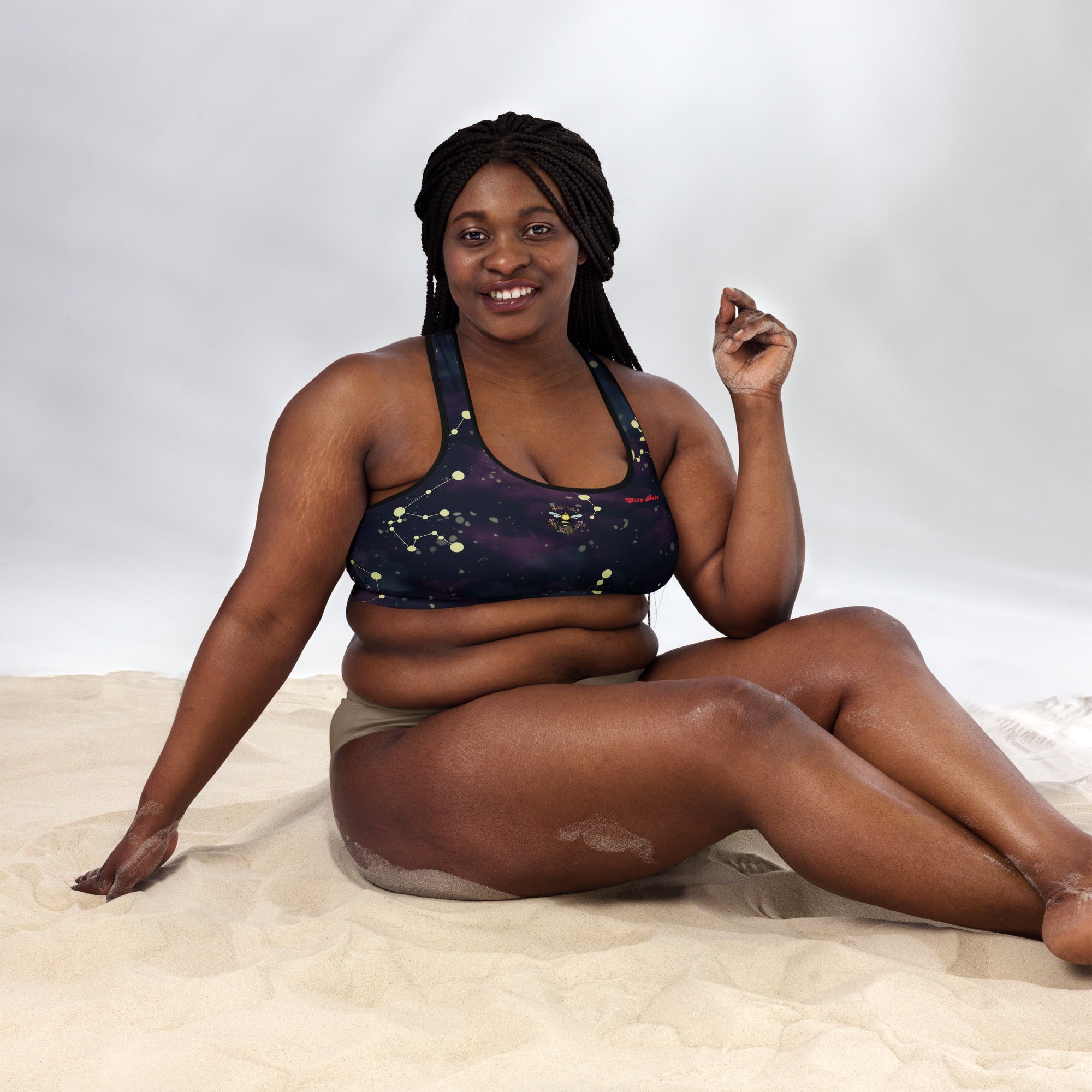 A model wearing The Andromeda Performance Bra, showing the supportive fit, yellow constellation print, and City Babe  text