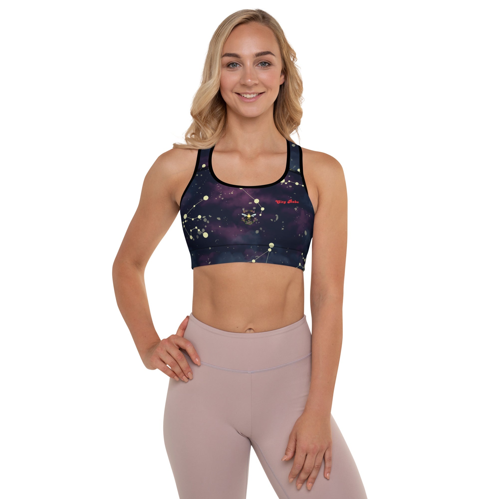 A model wearing The Andromeda Performance Bra, showing the supportive fit, yellow constellation print, and City Babe text