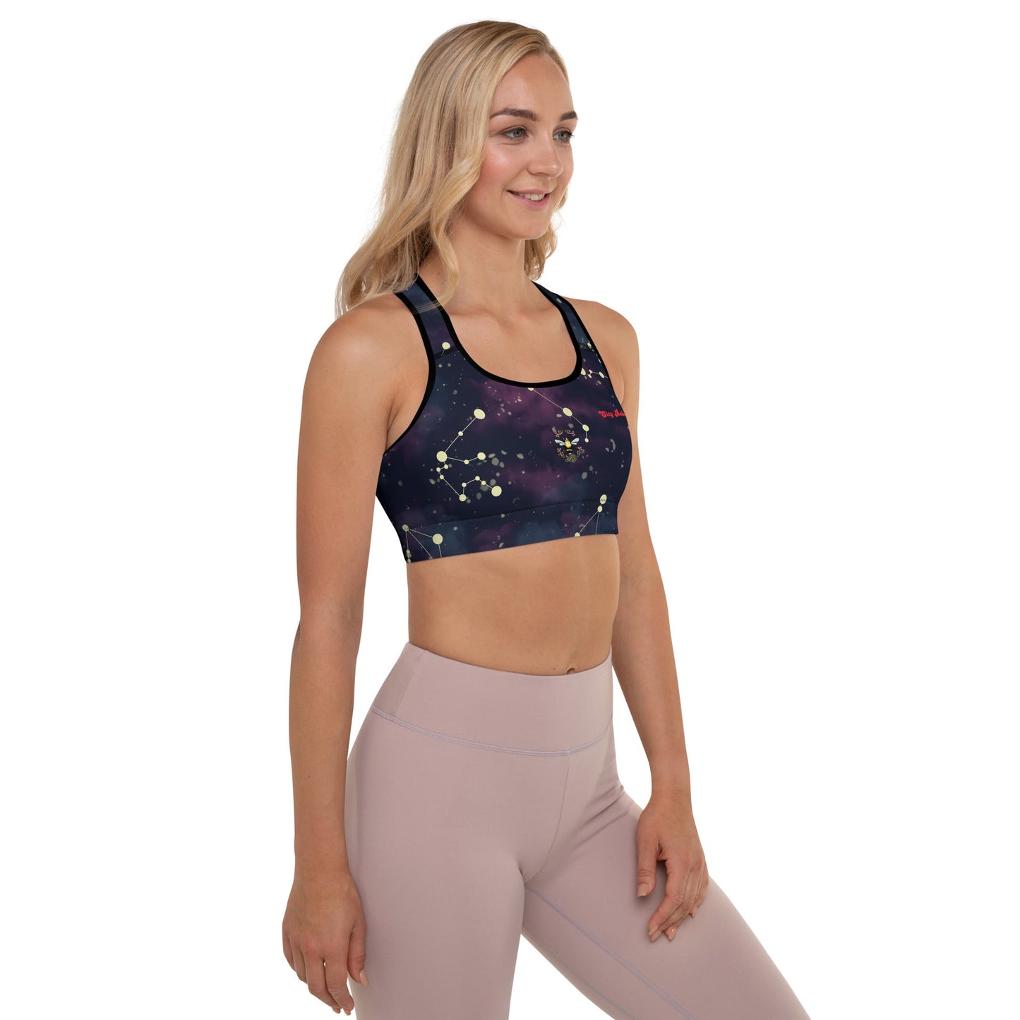 A model wearing The Andromeda Performance Bra, showing the supportive fit, the yellow constellation print, and the "City Babe" text on the dark purple/black gradient fabric.