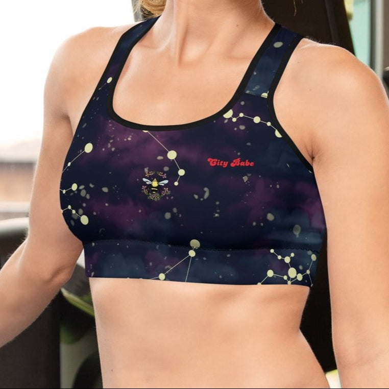 A model wearing The Andromeda Performance Bra, showing the supportive fit,yellow constellation print, and the City Babe text