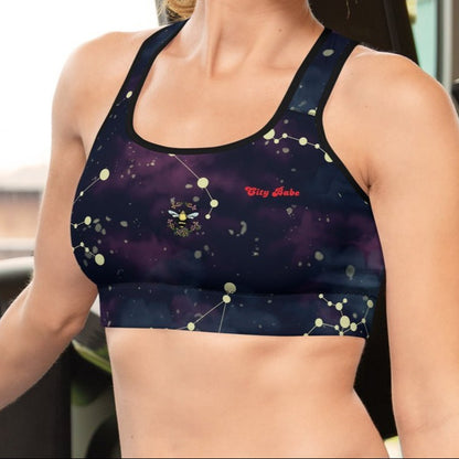 A model wearing The Andromeda Performance Bra, showing the supportive fit,yellow constellation print, and the City Babe text