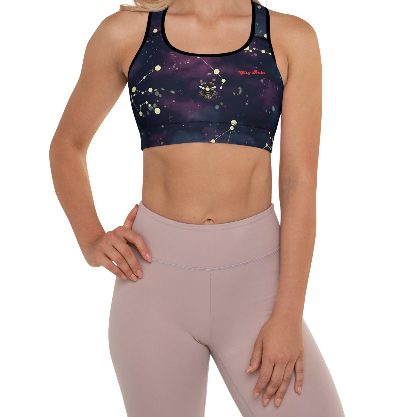 A model wearing The Andromeda Performance Bra, showing the supportive fit, yellow constellation print, and City Babe text