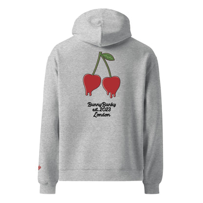 A close-up of the back of The Angel Wellness Hoodie, featuring the playful, pop-art cherry print and the heritage signature on the sleeve.