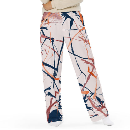 A woman modeling the angle flow wide-leg pants with an abstract paint stroke pattern in navy, orange, and pink on a cream background, paired with a cream long-sleeve top, against a solid white background.