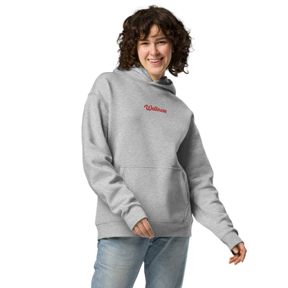 A model wearing The Angel Wellness Hoodie, showing the oversized fit and the embroidered "Wellness" text on the chest.