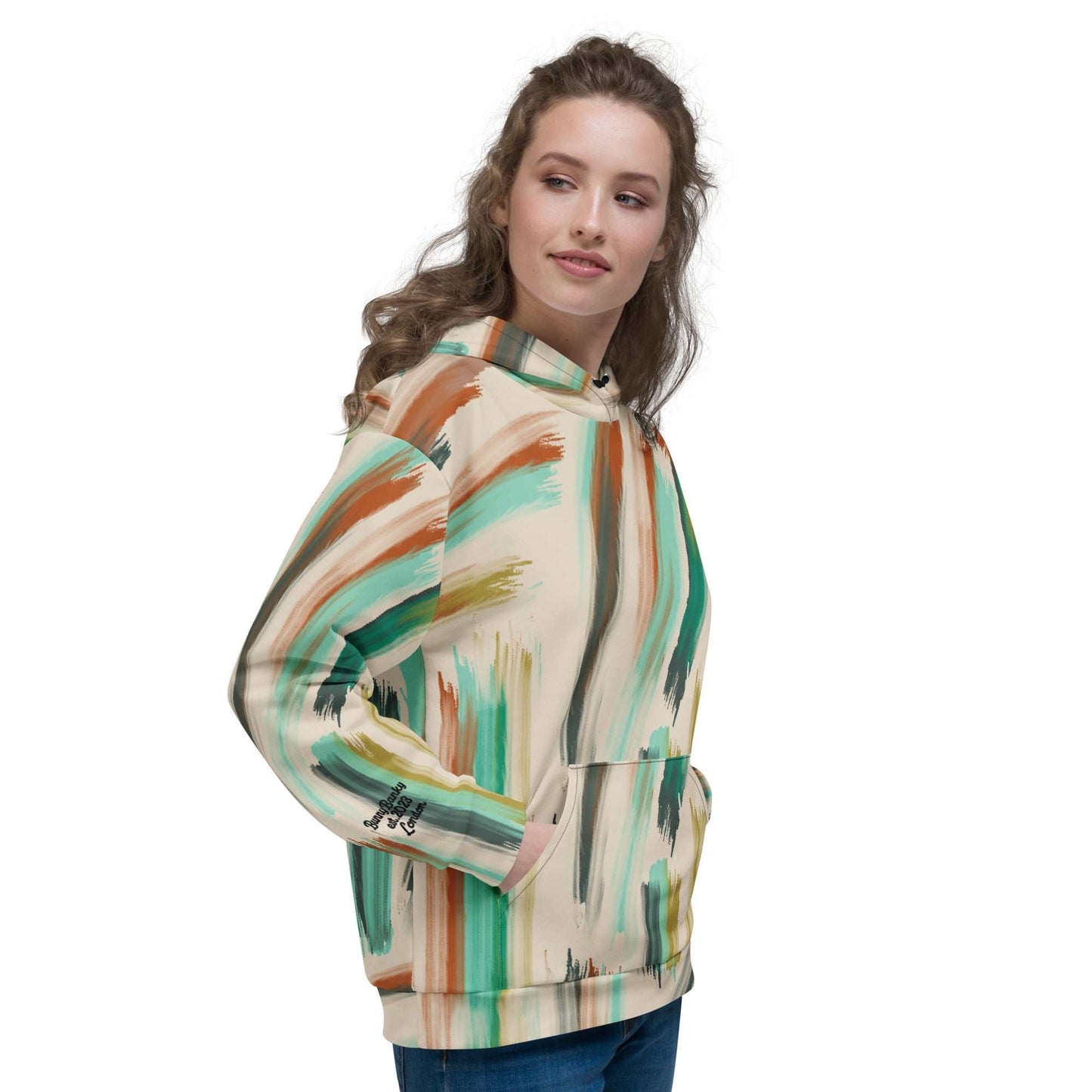 A model wearing The Artful Aura Hoodie, showing the relaxed, oversized fit and the soft pastel green brushstroke print on a beige background.
