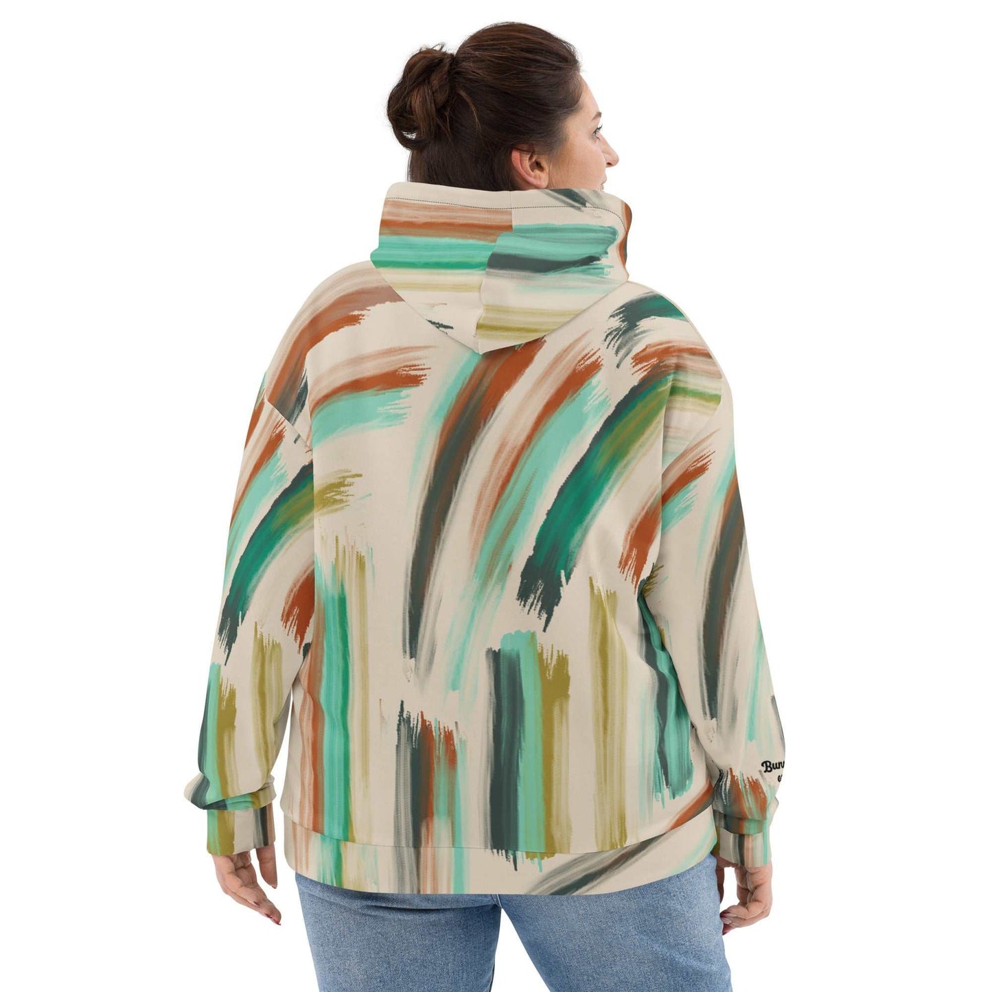A model wearing The Artful Aura Hoodie, showing the relaxed, oversized fit and the soft pastel green brushstroke print on a beige background.