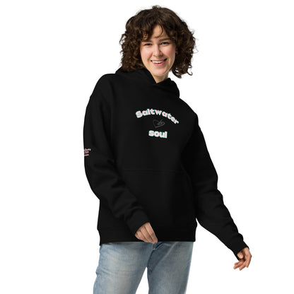 A model wearing The Azimuth Oversized Hoodie, showing the relaxed fit, drawstring hood, and "Saltwater Soul" text arched around the heart logo on the chest.