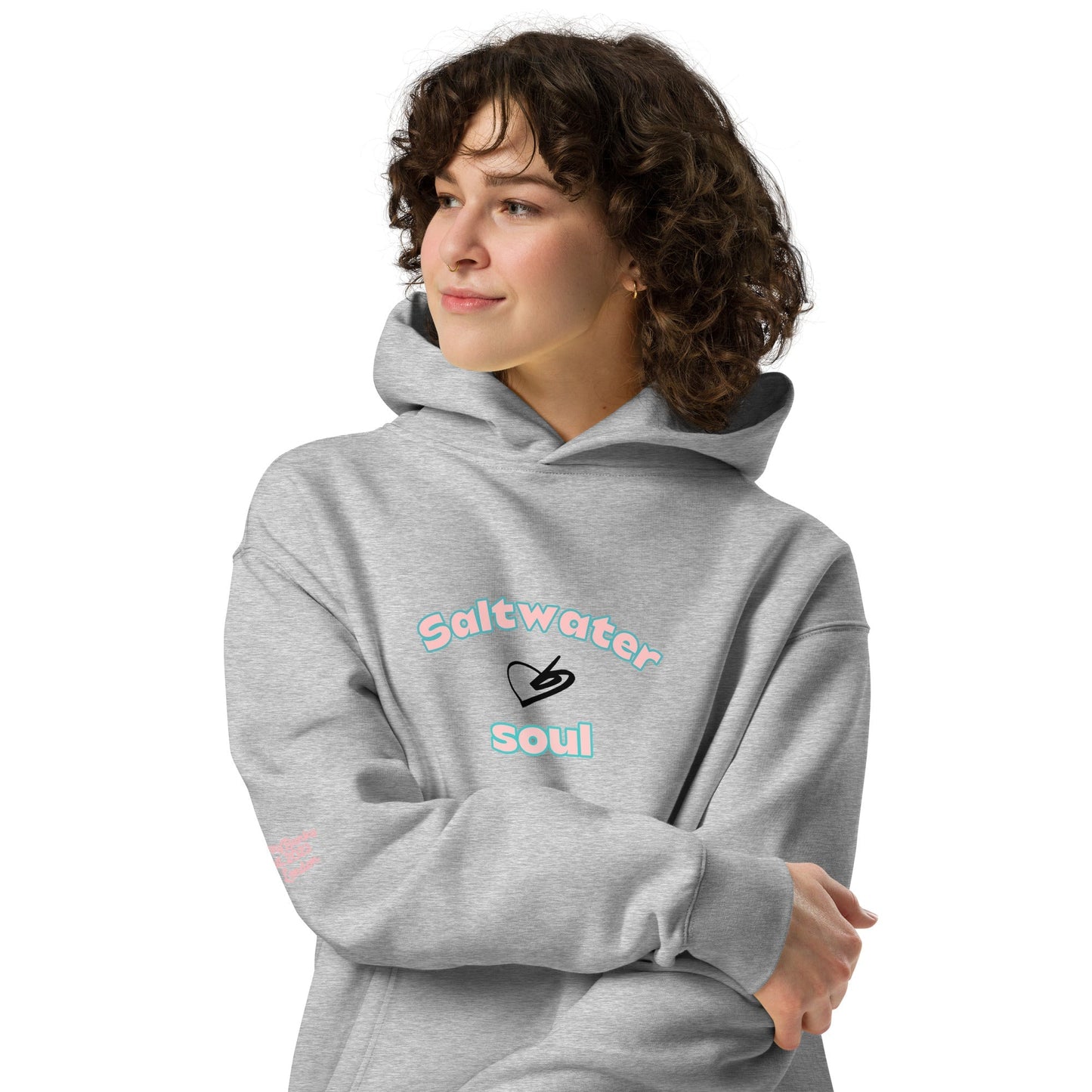 A model wearing The Azimuth Oversized Hoodie, showing the relaxed fit, drawstring hood, and "Saltwater Soul" text arched around the heart logo on the chest.