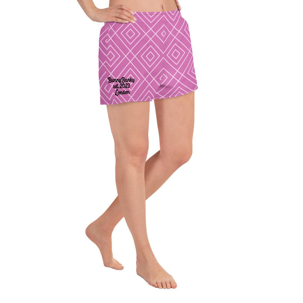 A model wearing the Bahamas Athletic Shorts, featuring an elaborate pink and white geometric lattice print.