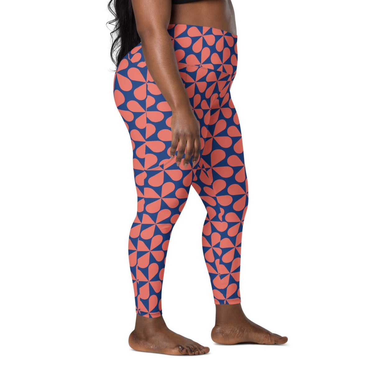Model wearing the  Bakerloo Sculpt Leggings in geometric pattern in blue with coral background.