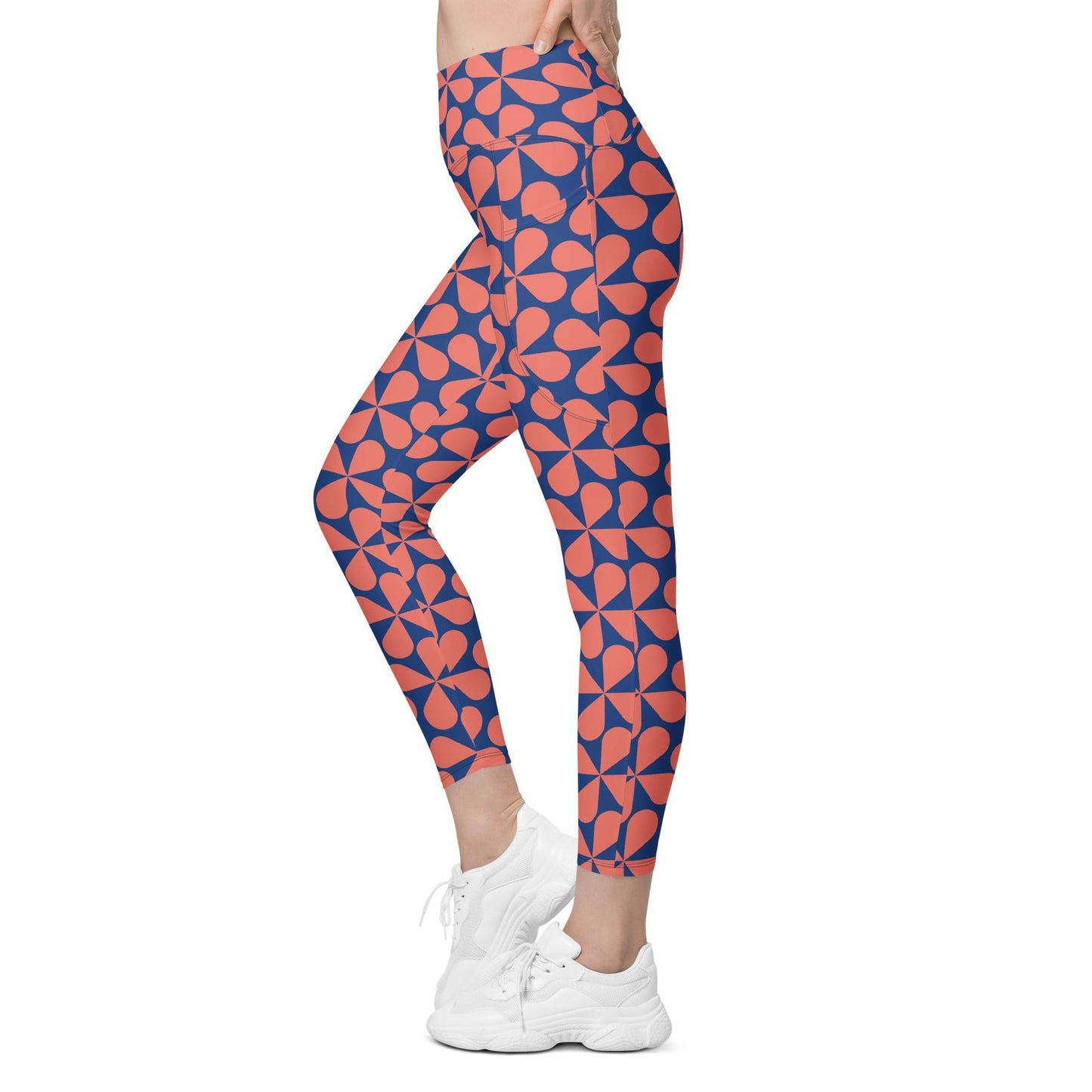 Model wearing the  Bakerloo Sculpt Leggings in geometric pattern in blue with coral background.