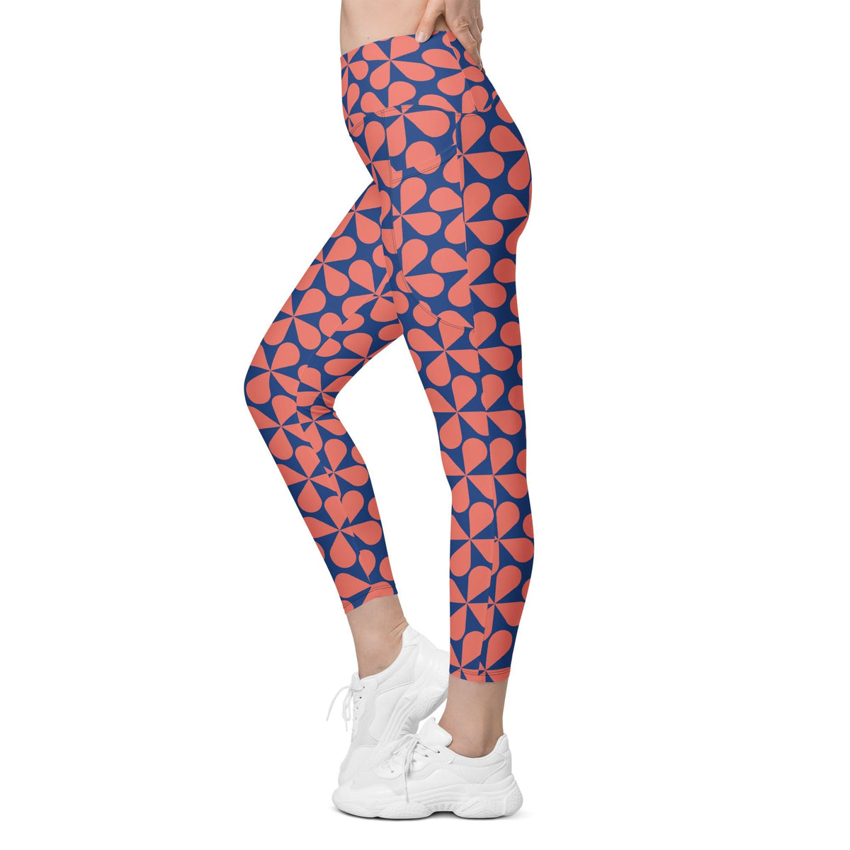 Model wearing the  Bakerloo Sculpt Leggings in geometric pattern in blue with coral background.