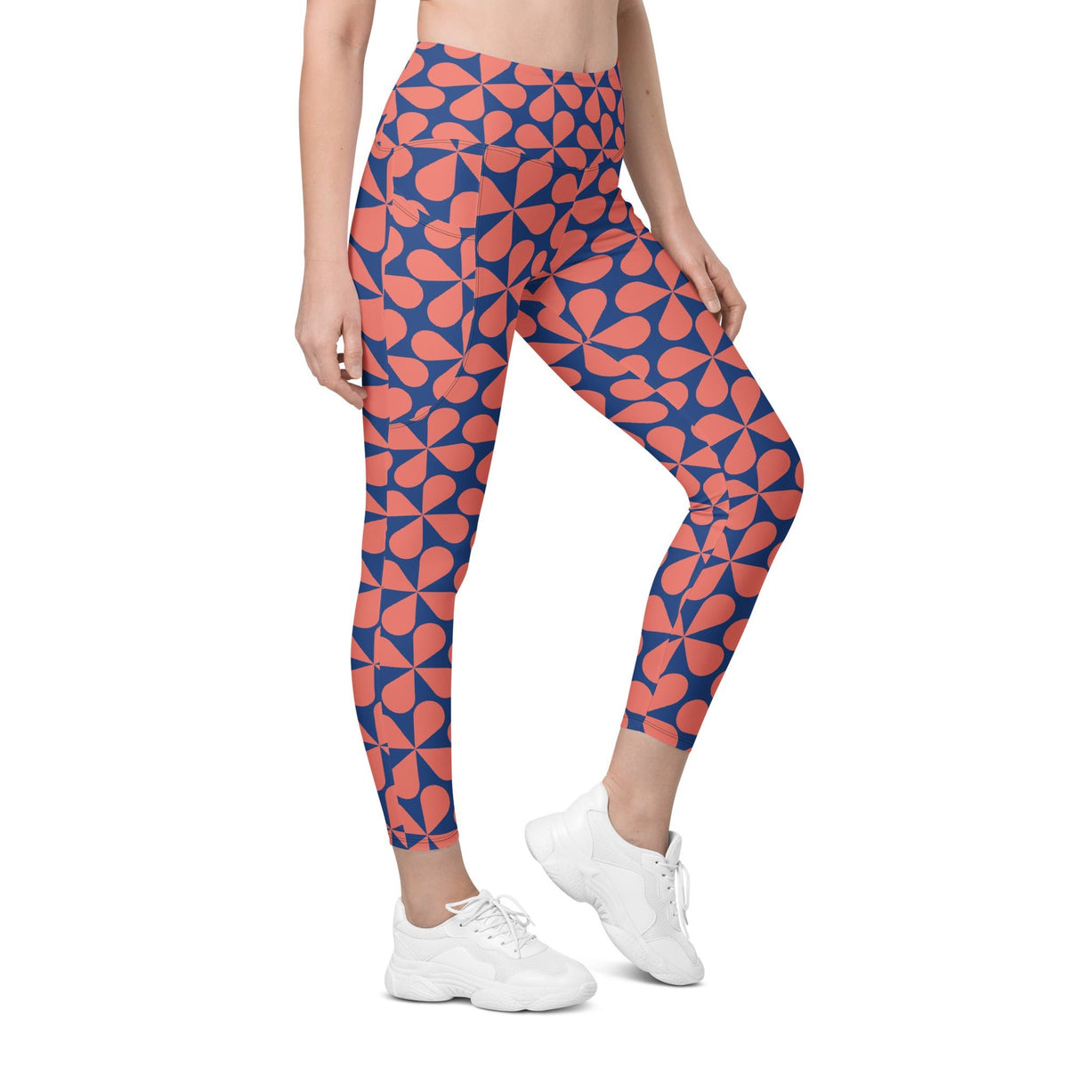 Model wearing the  Bakerloo Sculpt Leggings in geometric pattern in blue with coral background.